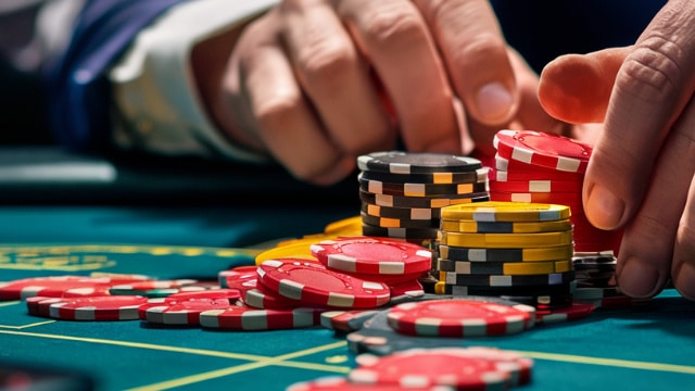 Ruke igra?a dok sortira raznobojne žetone na poker stolu, naglašavaju?i veli?inu uloga