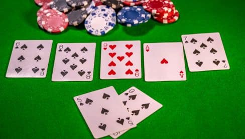 Texas Hold’em poker ruka sa zajedni?kim kartama i dve karte u ruci igra?a, okružena ?ipovima.