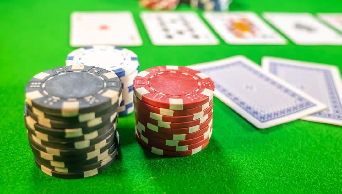 Pove?a slika poker ?ipova i karata na zelenom stolu tokom igre.