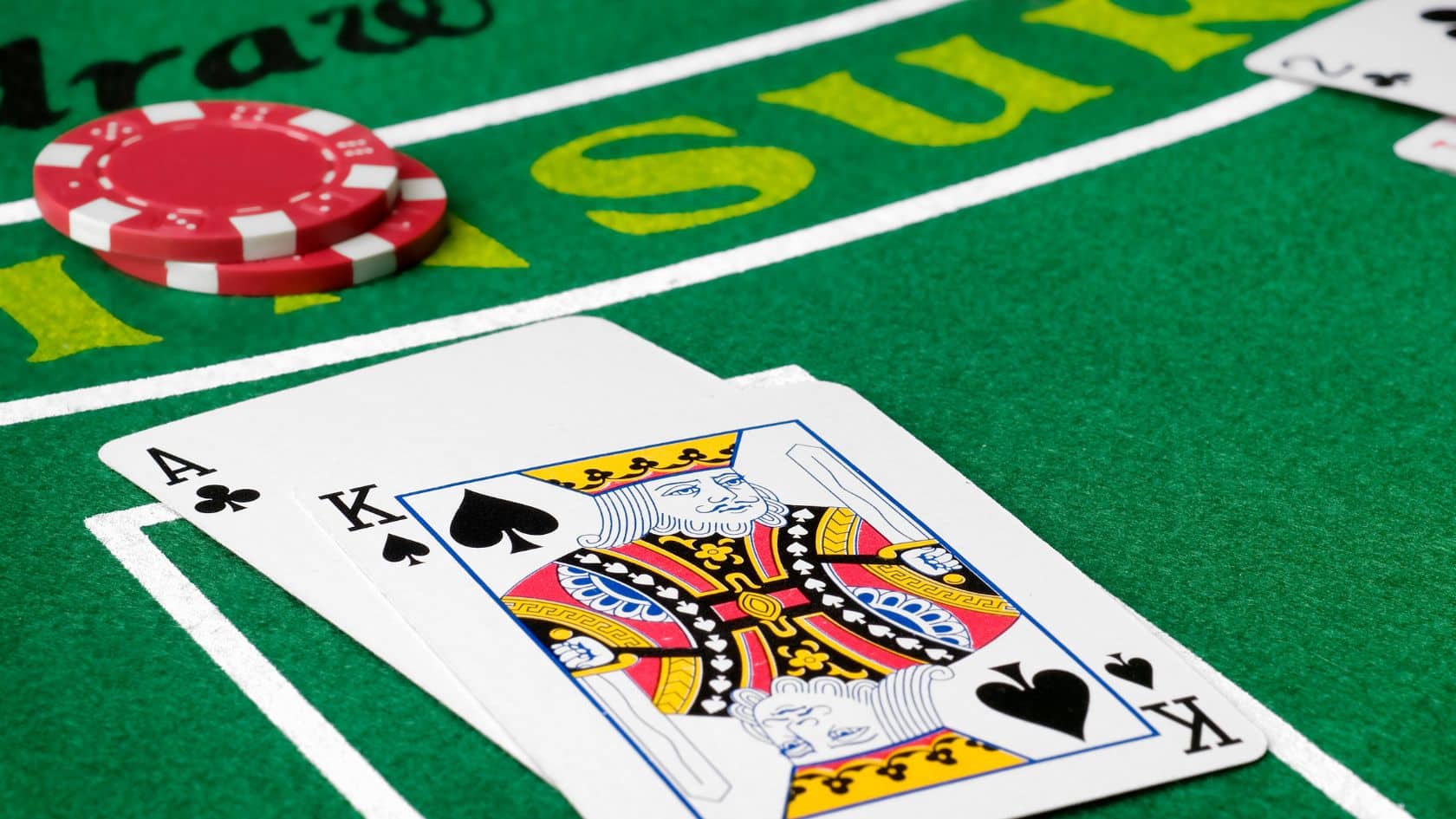 As tref i kralj pik na zelenom stolu za blackjack, uz crvene žetone.