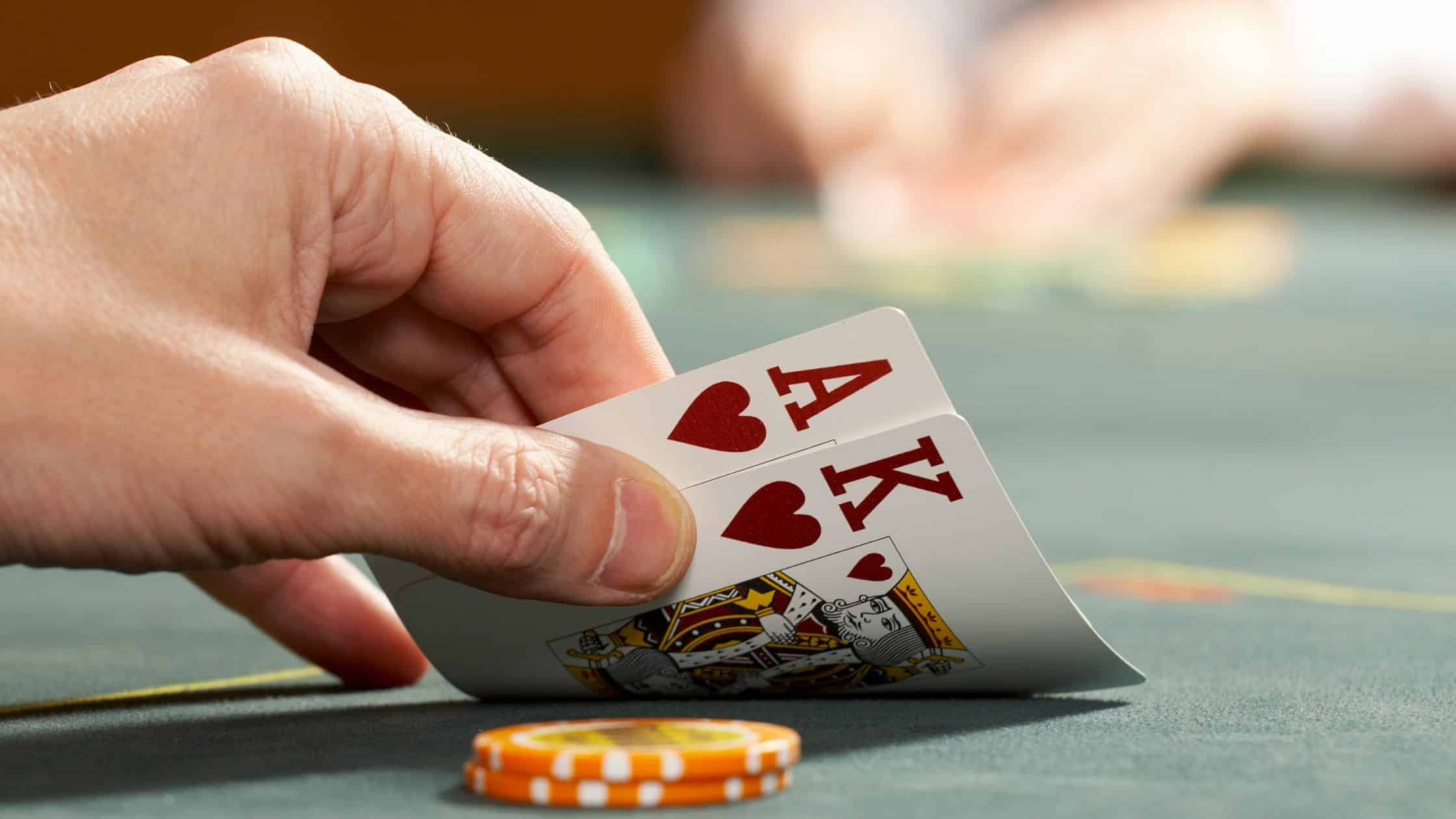 Igra? otkriva ruku sa Asom i Kraljem herc tokom Texas Hold’em partije.