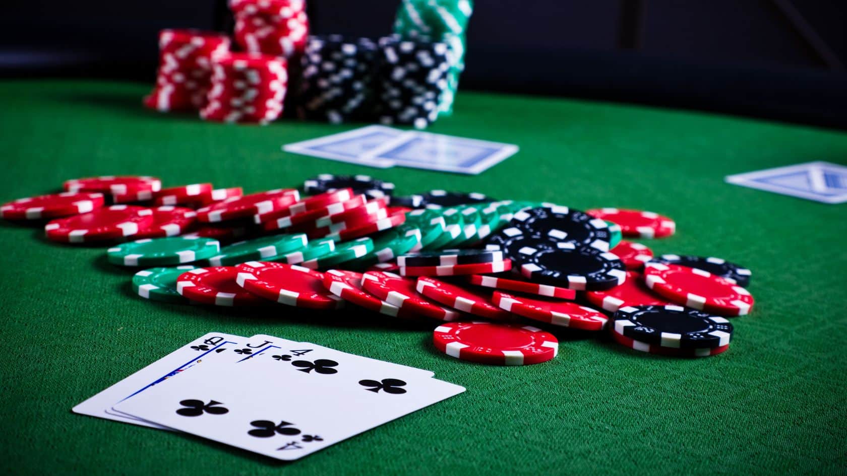 Krupan plan poker karata i žetona na zelenom stolu, u fokusu ke?evi i de?ko tref.