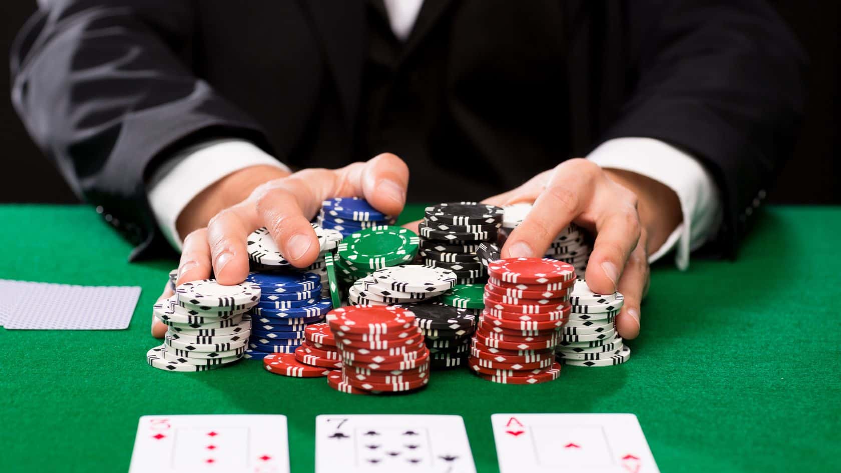 Igra? u odelu privla?i prema sebi veliku gomilu žetona na poker stolu.