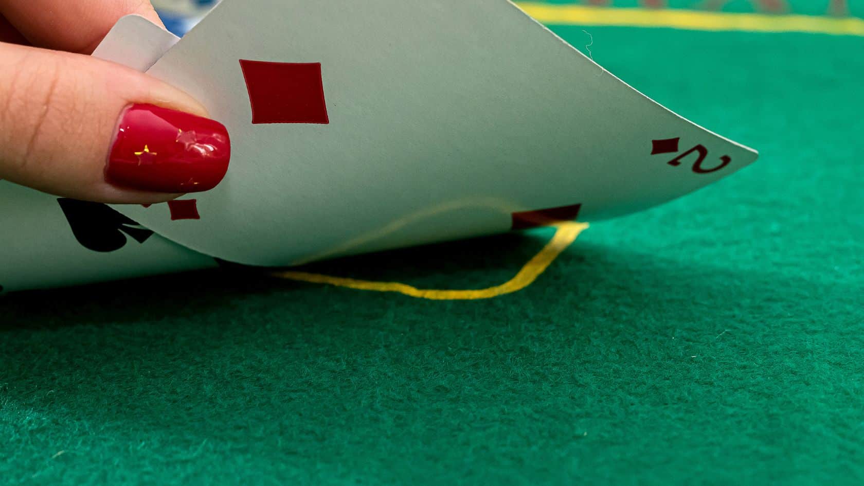 Igrač otkriva karte – ženska ruka podiže karte s brojevima dva i sedam