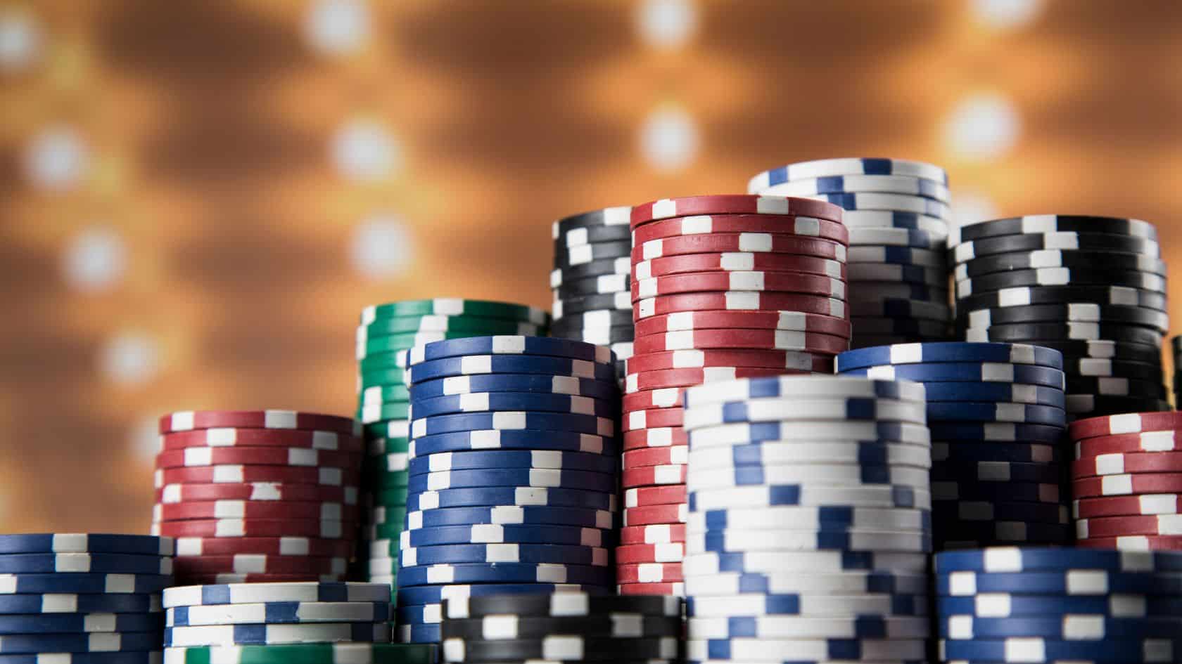 Piramida poker žetona u raznim bojama ispred zamućene pozadine sa svetlima kazina.