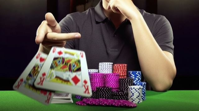 Igrač baca karte na sto pored velike gomile žetona u pokeru