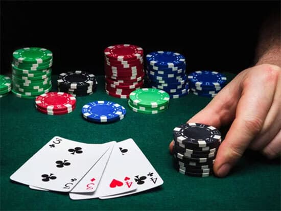 omaha game with hand pushing black chips with four cards up on the table