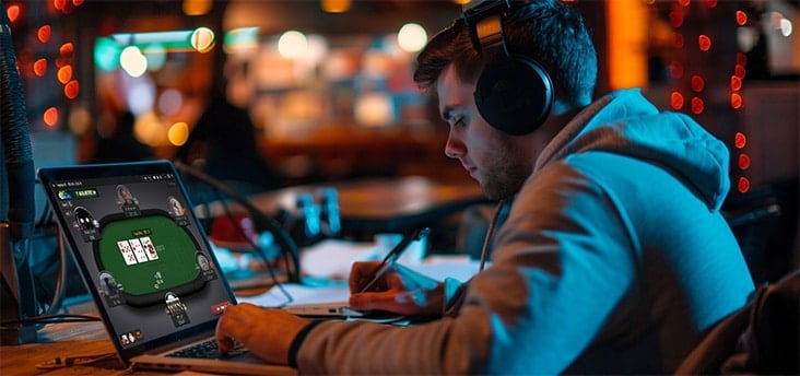 man in cafe with laptop playing online poker and taking notes